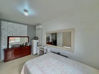 Quarto com cama e espelho em um ambiente claro.