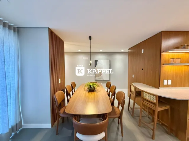 Uma sala de jantar com mesa de madeira e cadeiras em um apartamento.