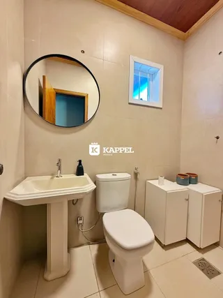 Foto de um banheiro com pia e vaso sanitário brancos.