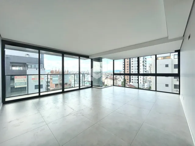 Sala de estar ampla com vista para a cidade através de grandes janelas.