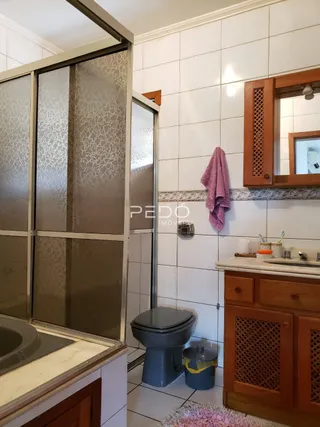 Foto de um banheiro com azulejos brancos e louças sanitárias.
