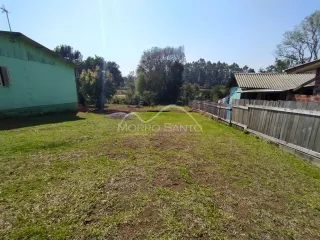 Vista externa de um terreno gramado com cerca de madeira.