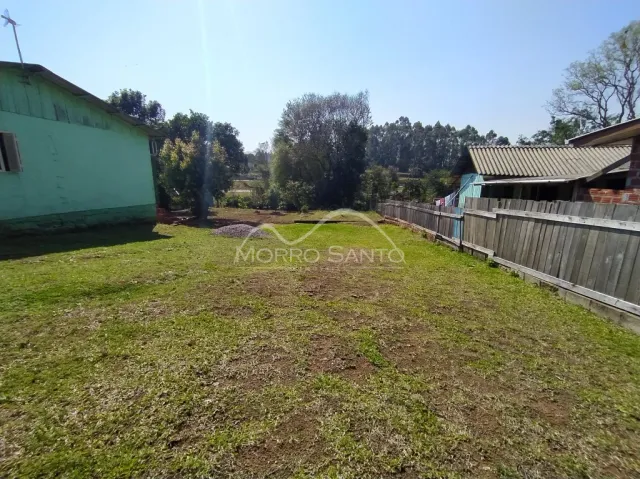 Vista externa de um terreno gramado com cerca de madeira.