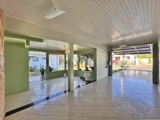 Ambiente interno com piso de cerâmica e grandes aberturas para o exterior.
