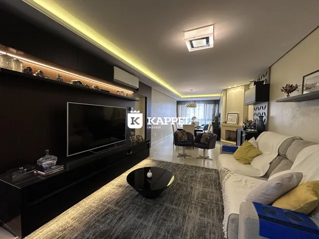 Sala de estar moderna com sofá e televisão em um ambiente bem iluminado.