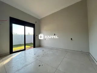 Ambiente interno de uma sala com piso de cerâmica e porta de vidro voltada para o exterior.