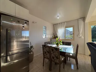 Uma sala de jantar com mesa de vidro e cadeiras de madeira.