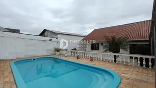 Piscina azul em frente à casa com fachada branca.