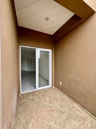 Vista de um corredor interno com piso de cerâmica e paredes em tom terroso.