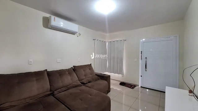 Sala de estar com sofá marrom e porta branca em um imóvel no Brasil.