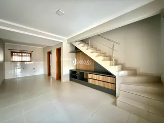 Vista interna de uma área ampla com piso de cerâmica e escadaria moderna.
