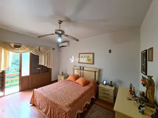 Quarto com cama de casal e piso de madeira clara.