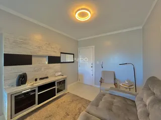 Sala de estar moderna com sofá e painel de TV em um apartamento.