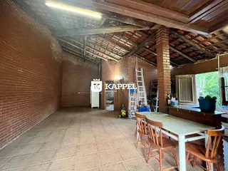 Interior de um espaço com paredes de tijolo aparente e teto de madeira exposta.