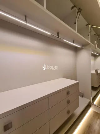 Vista de um ambiente interno com móveis brancos e iluminação moderna.