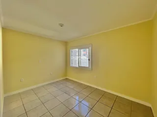 A foto mostra uma sala com paredes amarelas e piso de cerâmica clara.