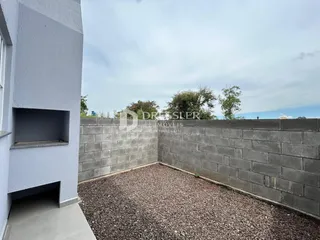 Parede externa de uma residência com um muro de concreto e terra no quintal.