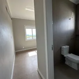 Foto de um corredor interno com paredes claras e piso claro.
