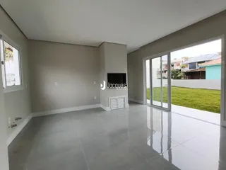 Sala de estar ampla com piso de porcelanato e portas de vidro que dão acesso ao jardim.