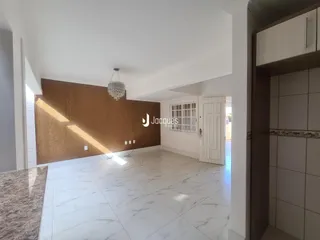 Ambiente interno de uma sala de estar com piso de mármore claro e parede de destaque marrom.