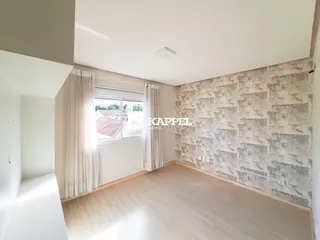Sala de estar com piso de madeira clara e janela com cortinas brancas.
