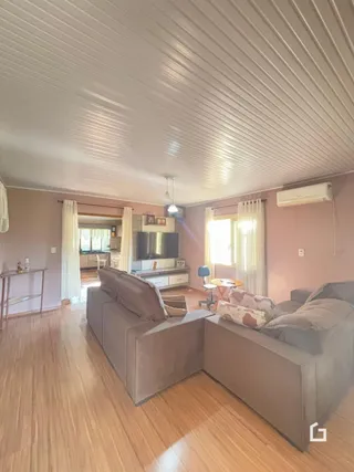 Sala de estar com piso de madeira e teto de painel na residência.