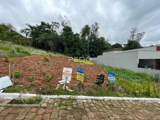 Foto da fachada de uma propriedade com encosta arborizada e sinalização.