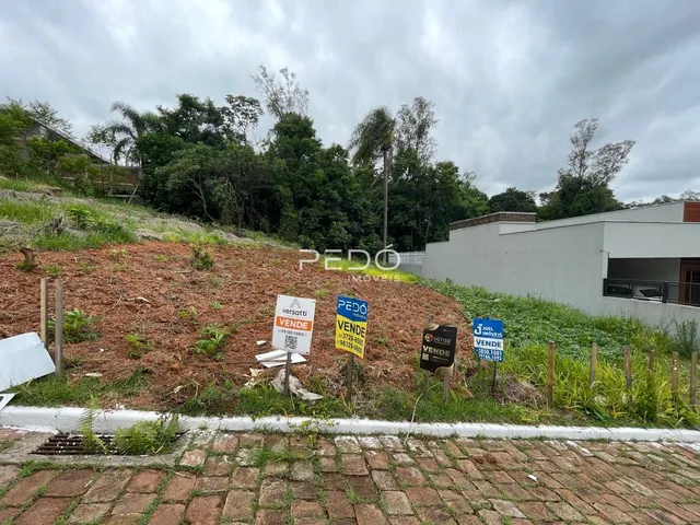 Foto da fachada de uma propriedade com encosta arborizada e sinalização.