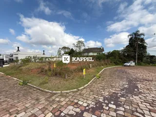Vista externa de uma propriedade com paisagismo e uma estrada de paralelepípedos.