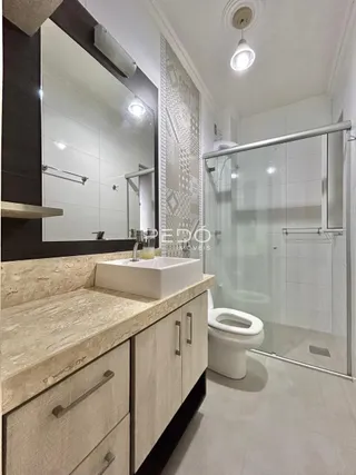 Foto de um banheiro moderno com box de vidro e bancada de mármore.