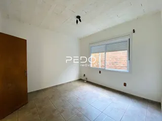 Ambiente interno de uma sala com piso de cerâmica e parede branca.