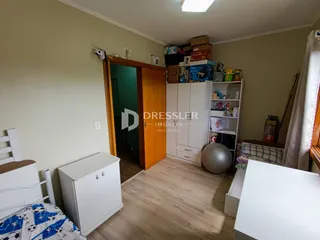 Quarto com piso de madeira e armários brancos em Lajeado.