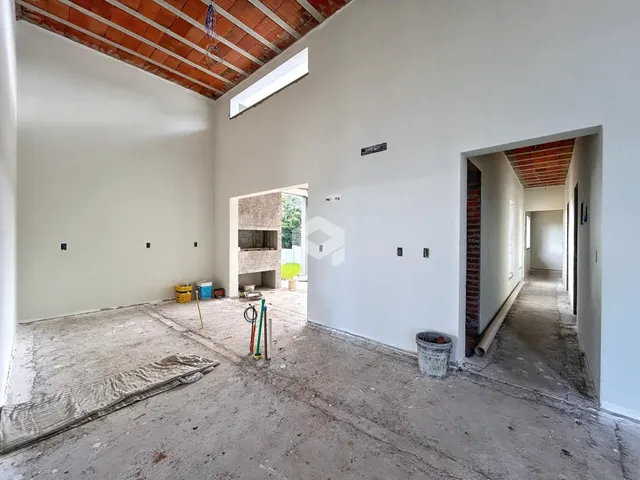 Interior de uma sala em construção com piso de concreto e teto de madeira exposto.