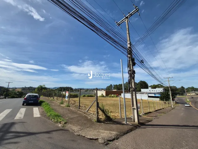 Vista externa de uma propriedade ao longo de uma estrada com postes de energia e cerca.