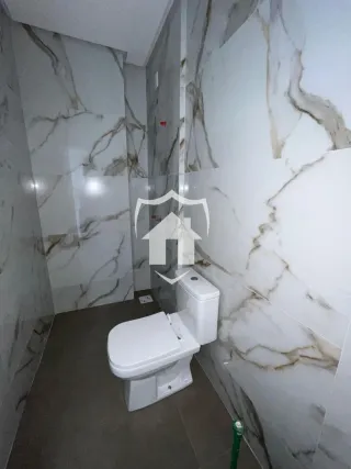 Foto do interior de um banheiro com paredes de mármore branco.