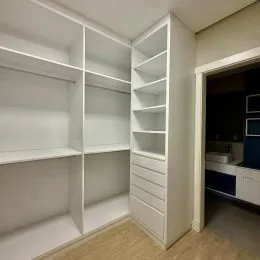 Uma estante branca com prateleiras está visível na imagem.