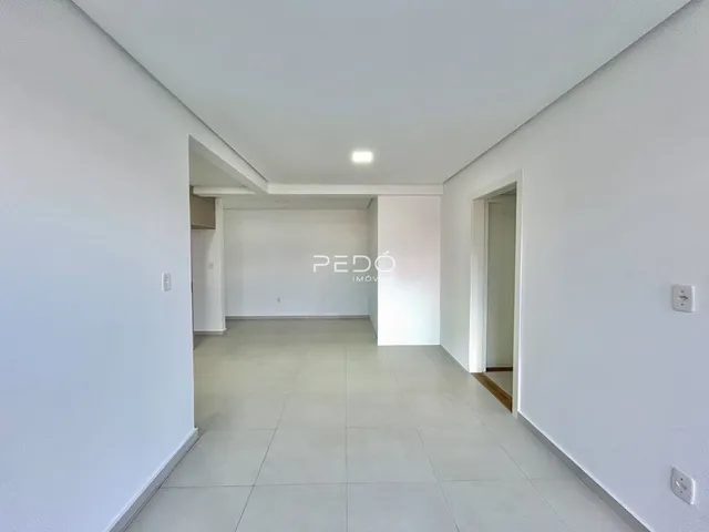 Corredor interno de uma residência com paredes brancas e piso claro.