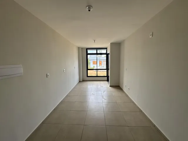 Corredor interno com paredes brancas e piso de cerâmica.