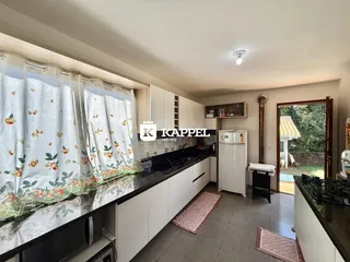 Cozinha moderna com armários brancos e bancadas escuras.