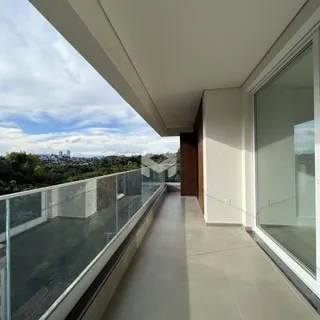Vista da varanda com grade de vidro e paisagem urbana.