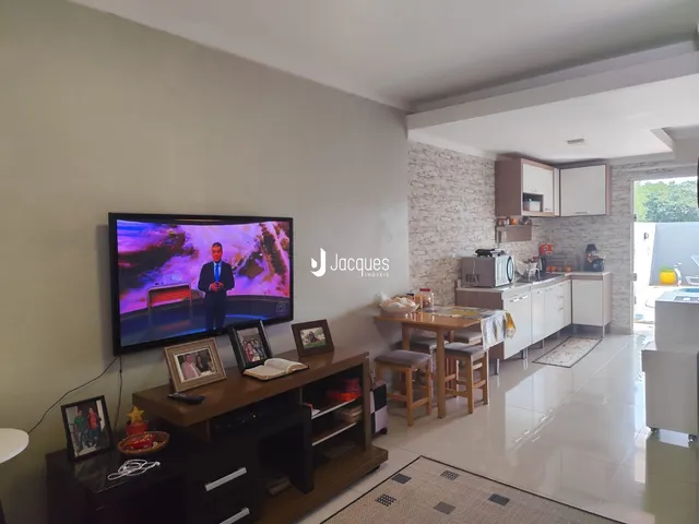 Sala de estar com televisão e área de jantar em um imóvel no Brasil.