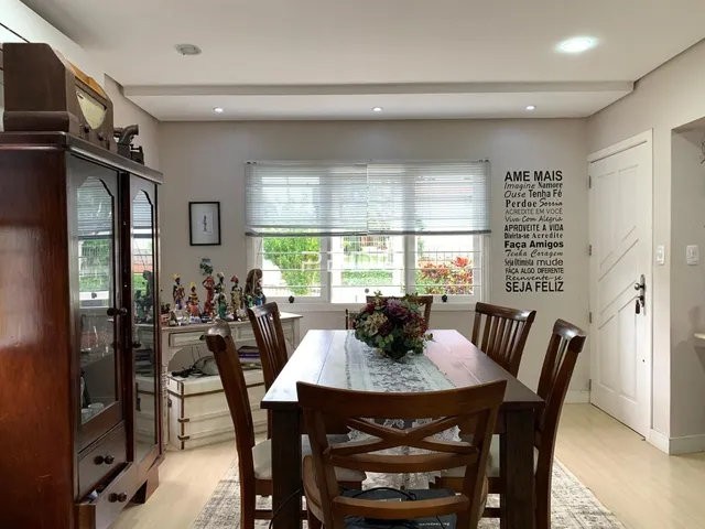 Uma sala de jantar com mesa de madeira e cadeiras em um imóvel no Brasil.