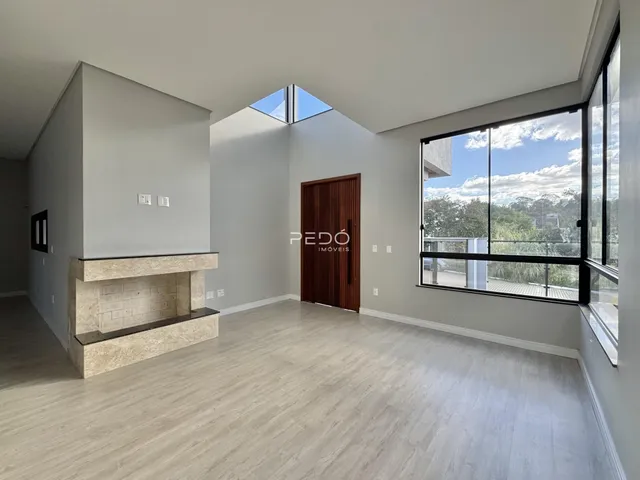 Sala de estar ampla com piso de madeira clara e grande janela.