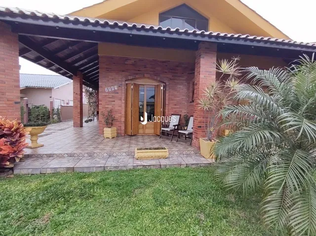 Fachada de casa em tijolo aparente com área coberta e jardim.