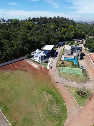 Vista aérea de uma propriedade com área gramada e vegetação densa ao redor.