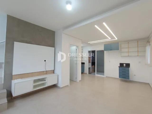 Sala de estar ampla com paredes brancas e piso claro.