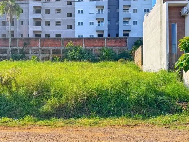 Vista externa de um prédio residencial com vegetação alta no primeiro plano.