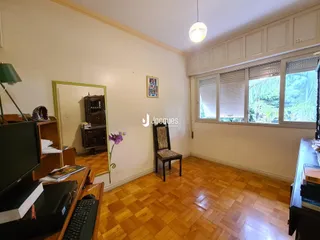 Ambiente interno de uma sala com piso de madeira e grandes janelas.