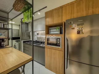 Vista interna de uma cozinha moderna com armários de madeira e eletrodomésticos.