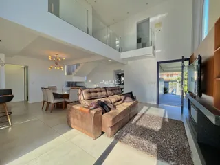 Sala de estar ampla com pé direito alto e vista para a área externa.